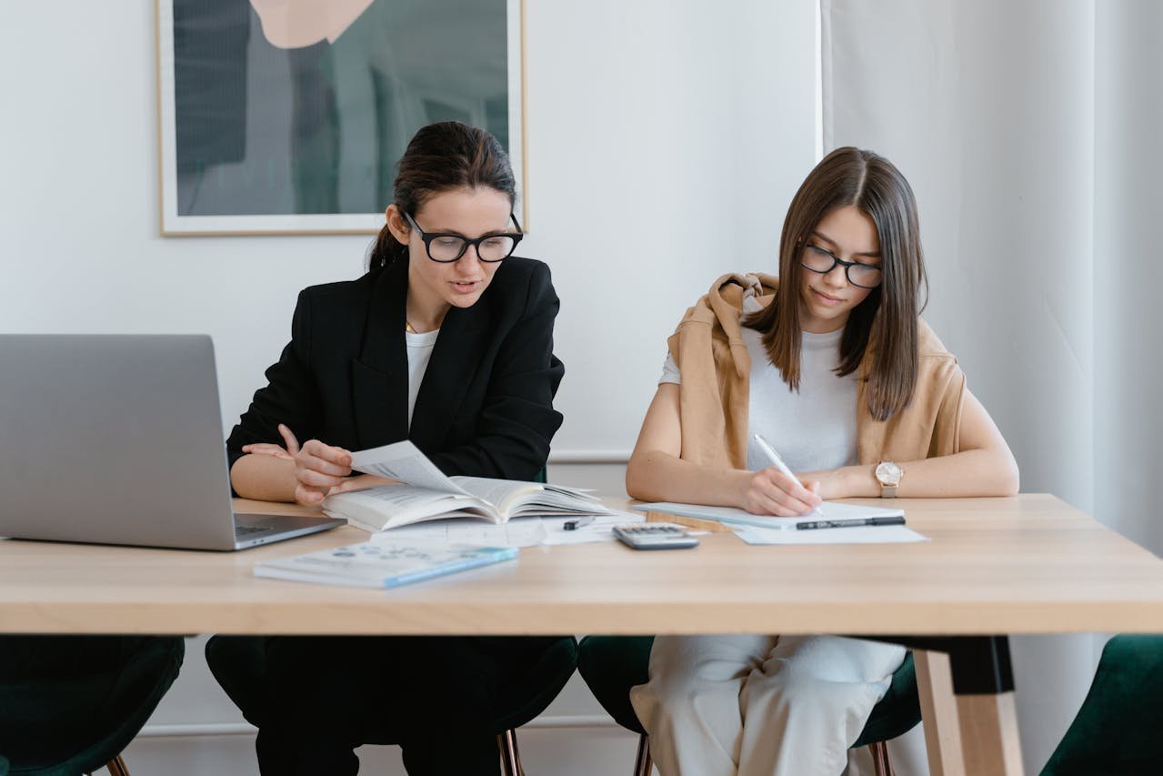 Dos estudiantes sentadas en un escritorio leyendo