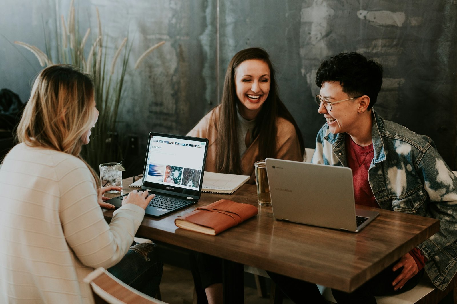 Tres personas en un escritorio con portátiles y sonriendo